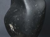 an image of a black stone sculpture on a wooden stand