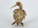 a close up of a gold bird brooch with pink and green stones