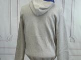 grey hoodie on a mannequin stand in front of a white wall