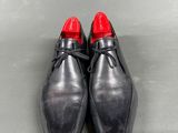 a pair of black shoes with red soles sitting on a gray surface