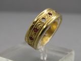 Gros plan sur une bague en or ornée de pierres rouges