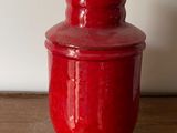 a red vase sitting on a table with a white wall in the background