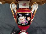 a red vase with flowers on it sitting on a table