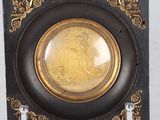 a black and gold plate with a picture of a woman on it