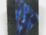 un vieux livre à la couverture bleue posé sur une table blanche