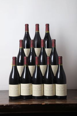 six bouteilles de vin sont posées sur une table en bois devant un mur blanc