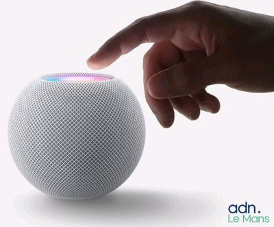 une personne montrant du doigt une enceinte HomePod blanche posée sur une surface blanche