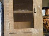 une armoire en bois avec une porte vitrée, posée sur une étagère