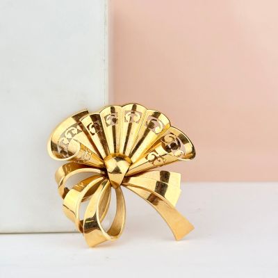 gold plated ring with a fan shaped design on top of a white box