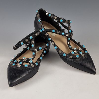 a pair of black leather shoes with turquoise stones on the toes