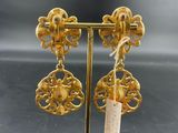a pair of gold earrings on a stand with a price tag