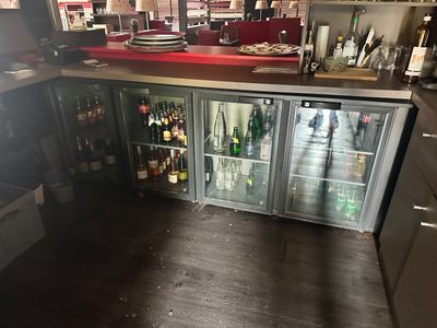 Des bouteilles de vin sont alignées derrière une porte vitrée dans un bar