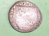 an old silver coin sitting on top of a green surface