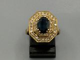 un gros plan d'une bague en or sertie d'une pierre bleue entourée de diamants blancs