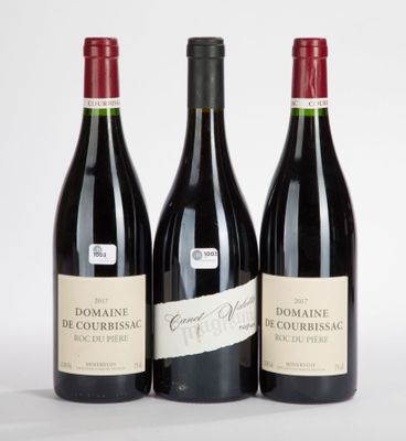 three bottles of red wine sitting next to each other on a white surface