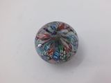 glass bead with multicolored swirl design on white surface