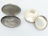 two silver plated pill cases sitting on top of a white surface