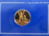 a gold coin with the image of a man and woman in a boat