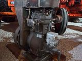 un petit moteur posé sur un socle en bois dans une grange