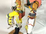 three wooden figurines of people dressed in different costumes