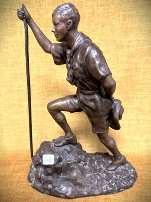 statue en bronze représentant un homme tenant un bâton, assis sur un rocher