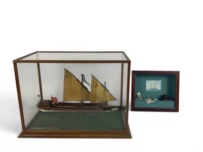 an old model of a ship in a glass case next to a framed picture