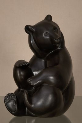 sculpture représentant un ours noir assis sur le dos sur une table