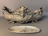 a silver plate with a face on it next to a mirror