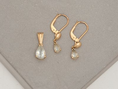 two pairs of earrings and a pendant on a white surface