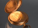 a gold pocket watch sitting on top of a glass table