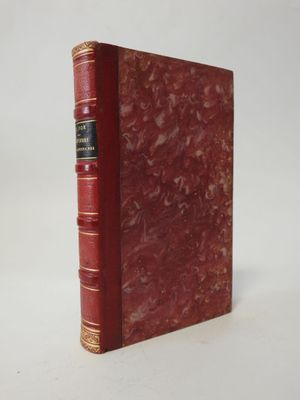 a red book with gold trim sitting on top of a white surface