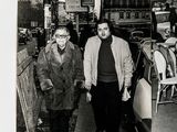 black and white photograph of two men walking down a sidewalk