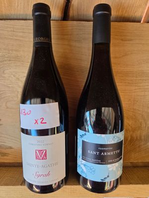 deux bouteilles de vin posées sur une étagère l'une à côté de l'autre