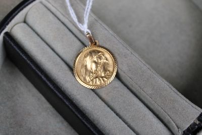une pièce d'or dans un étui muni d'un cordon blanc
