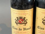 two bottles of red wine sitting next to each other on top of a table
