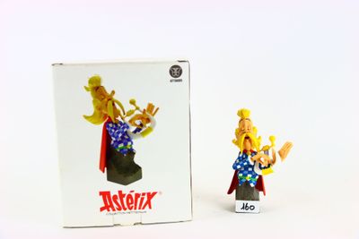 une figurine représentant un homme vêtu d'une cape, avec une boîte derrière lui