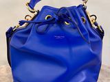 a blue bucket bag sitting on top of a white surface