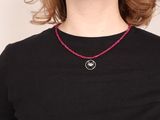 woman wearing a black shirt and a red beaded necklace with a smiley face on it