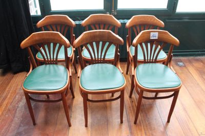quatre chaises en bois aux assises vertes, placées devant une fenêtre