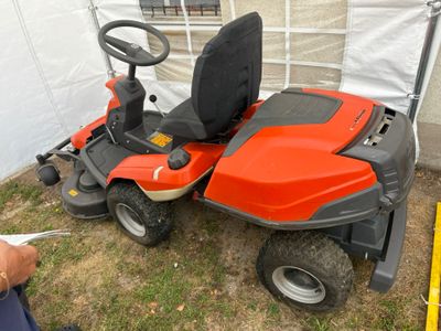 une tondeuse à gazon posée dans l'herbe à côté d'une tente