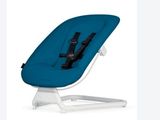 une chaise haute avec un siège bleu sur un piètement blanc