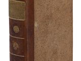 un vieux livre à la couverture brune posé sur une surface blanche