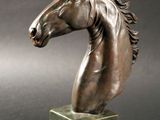 statue représentant une tête de cheval sur un socle, sur fond gris