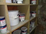 several buckets of paint sitting on a shelf in a room