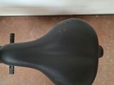 a black bicycle seat on the floor next to a wall