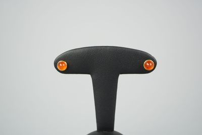 une photo en gros plan d'une paire de boucles d'oreilles à clous orange