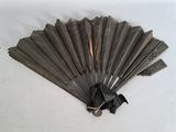 a black fan with a metal handle on a white surface