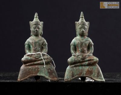 two bronze statues of buddhas sitting on top of a table