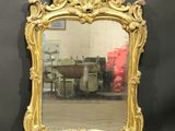 an image of a gold framed mirror sitting on top of a wooden floor