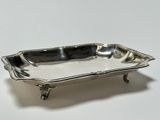 an antique silver plate on a stand on a white surface